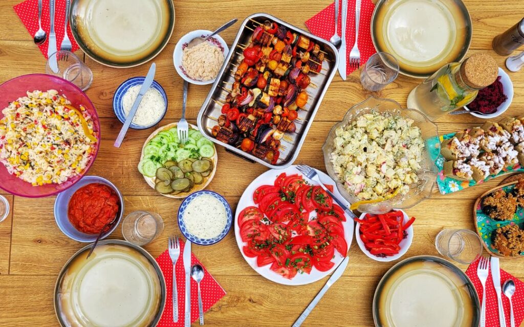 wegańskie jedzenie na stole, sałatki, szaszłyki, dipy, ciasto i świeże warzywa